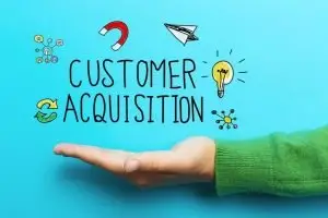 Open upturned palm in a green sweater beneath hand-drawn text "Customer Acquisition" with doodled magnet, paper plane and lightbulb icons on turquoise