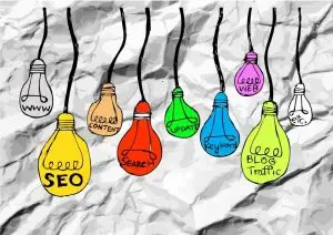 Hand-drawn colored lightbulbs hanging from cords on crumpled paper, each labeled with a term like "SEO", "Content", "Search", "Keyword" and "Blog Traffic"