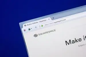 Corner of a monitor against a dark blue background showing the squarespace.com homepage with the Squarespace logo and "Make it" headline.