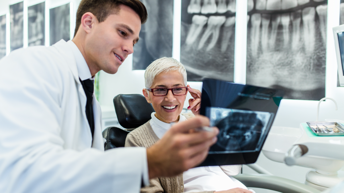 Dentist reviewing a dental X-ray with a smiling patient in the exam chair