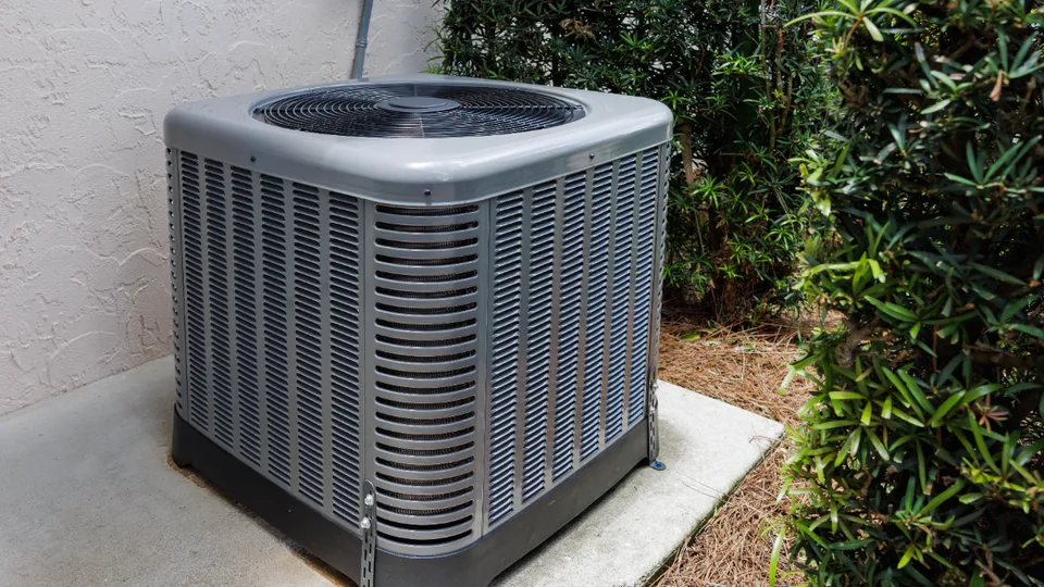 Outdoor HVAC air-conditioning condenser unit on a concrete pad beside a home