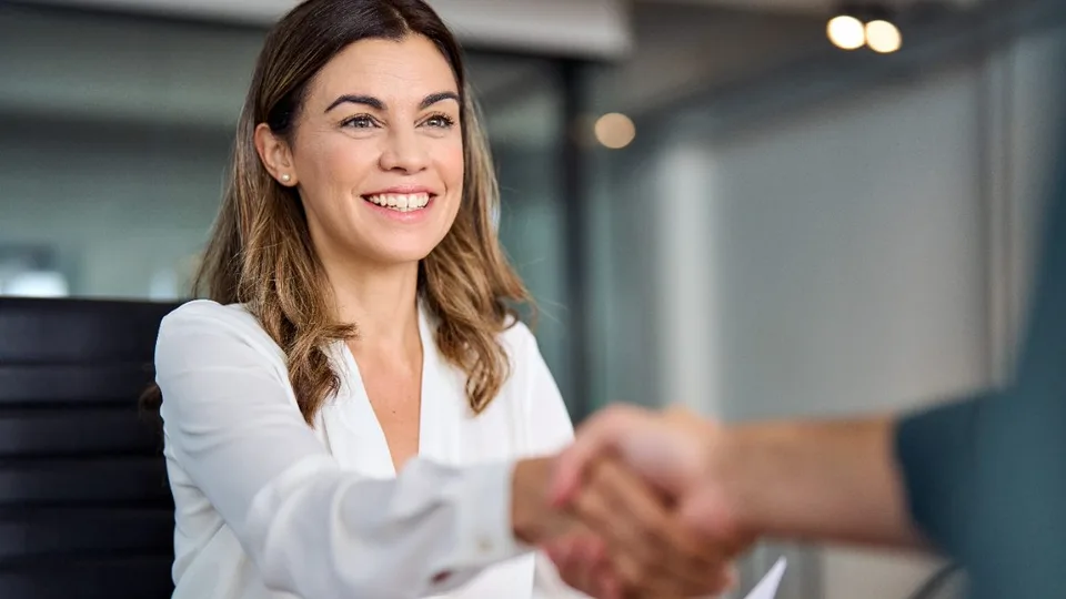 Attorney shaking hands with a new client across a desk with a signed agreement