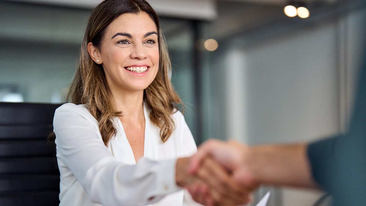 Attorney shaking hands with a new client across a desk with a signed agreement