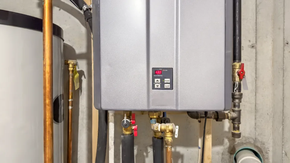 Wall-mounted tankless water heater with copper supply lines and valves in a home utility room